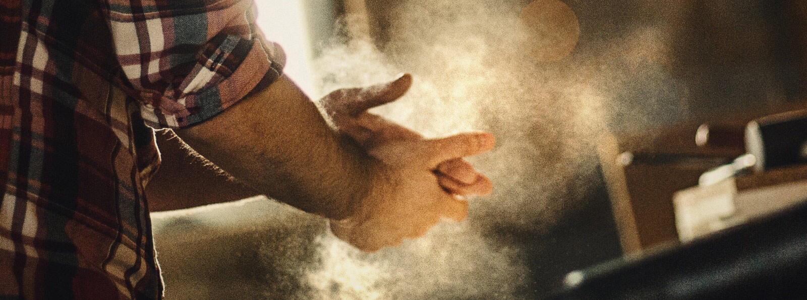 close-up of a man's hands dusting off sawdust 