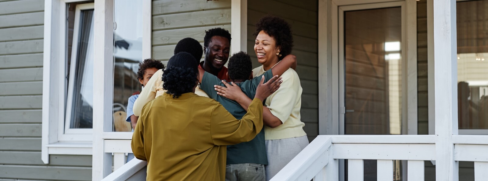 big family embracing in front of a house