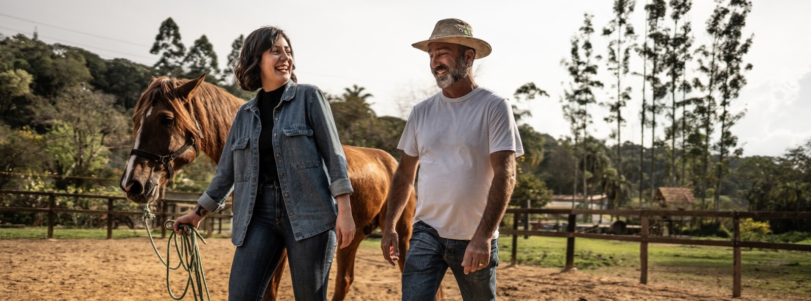 man and woman walking a horse in a fenced area