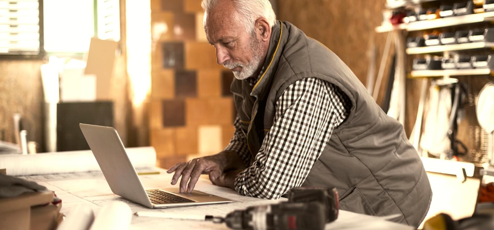 mature man using a laptop in a workshop